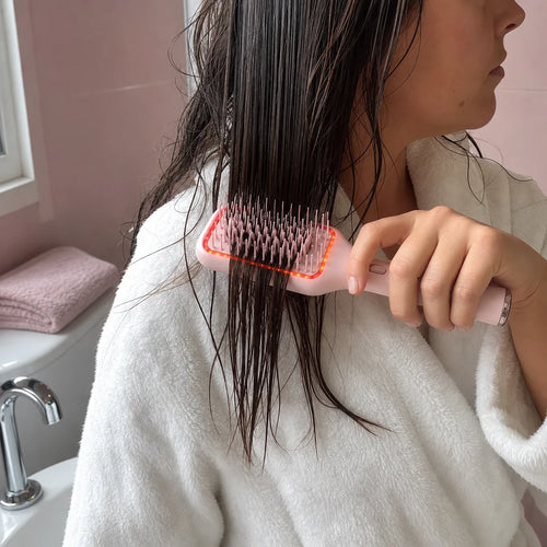 Freeze exactly one brief-defined action in a real bathroom after a shower: one woman guides the exac