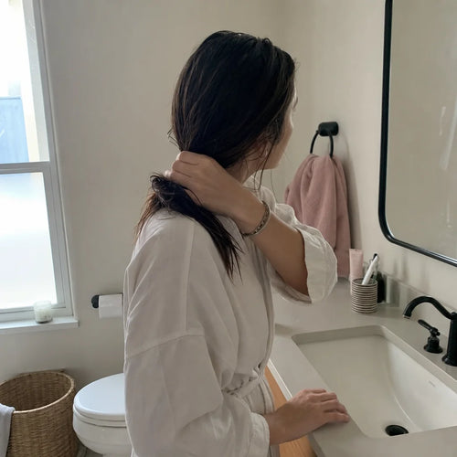 Authentic post-use lifestyle photograph, square aspect ratio, showing one woman in a real bathroom i
